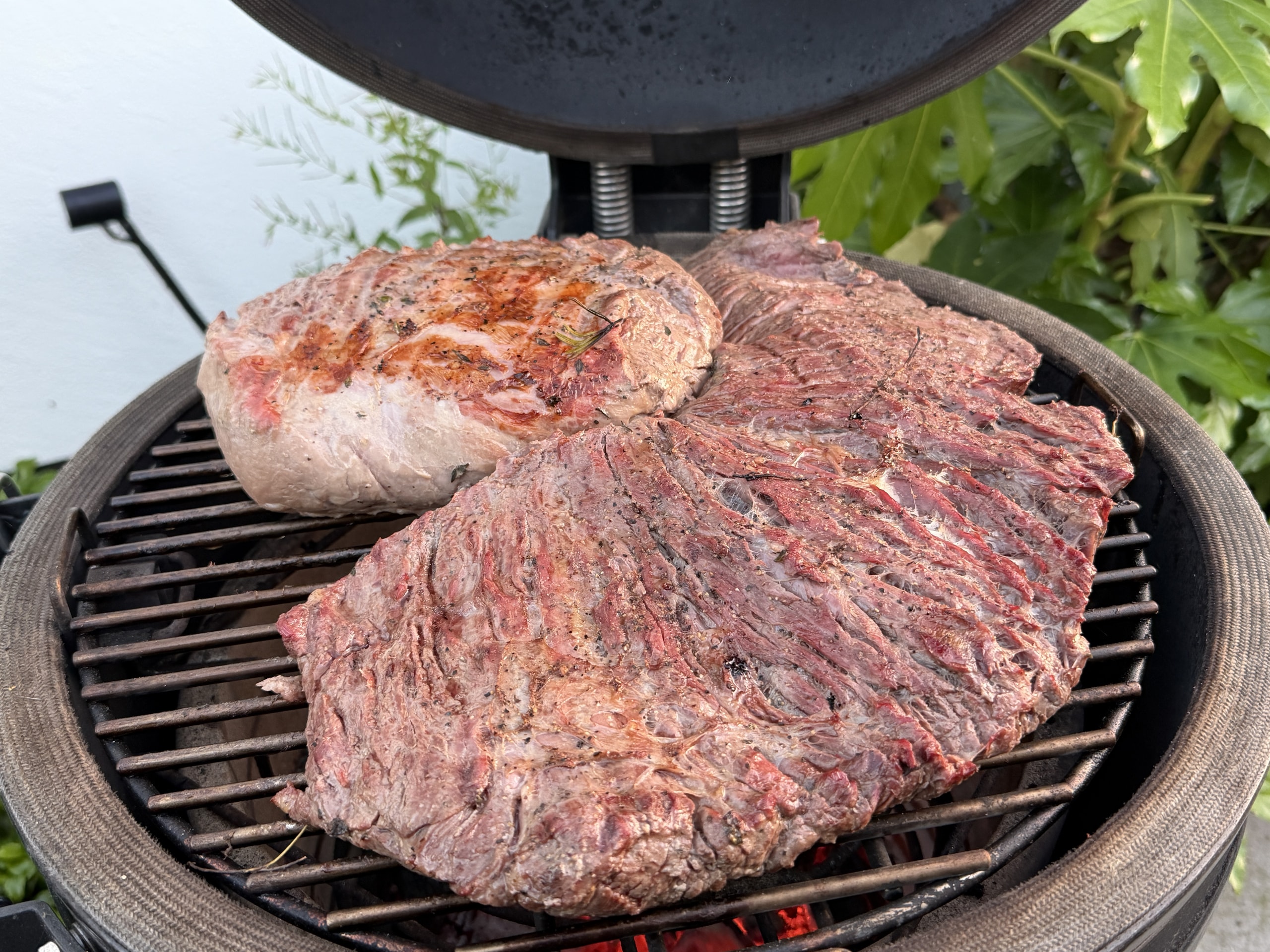 Twee grote stukken vlees op het rooster van een kamado.